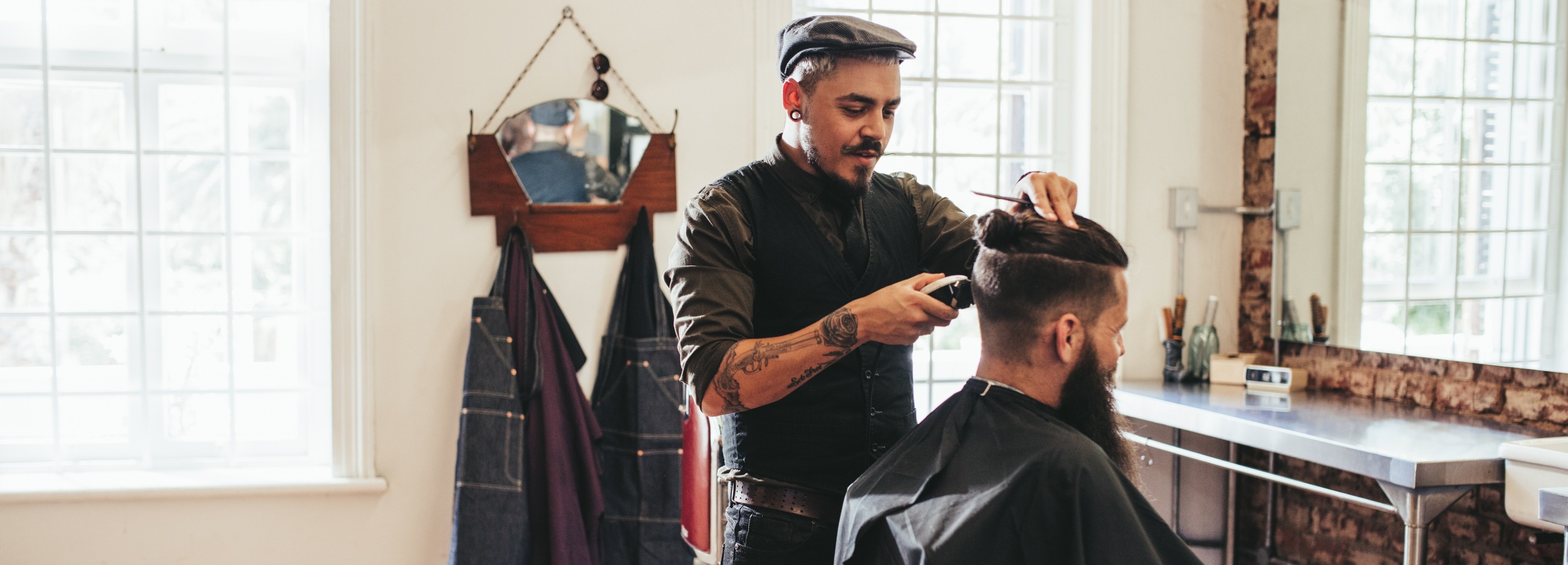 Ein Friseur macht einem Kunden in einem Friseursalon einen Haarschnitt.